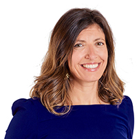 Smiling woman with shoulder-length brown hair in a blue top, looking at the camera against a white background.